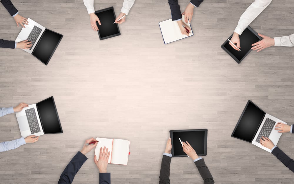 Group of people with devices in hands having desk discussion and making reports together on laptop, tablet, notebook Group of people with devices in hands having desk discussion and making reports together on laptop, tablet, notebook